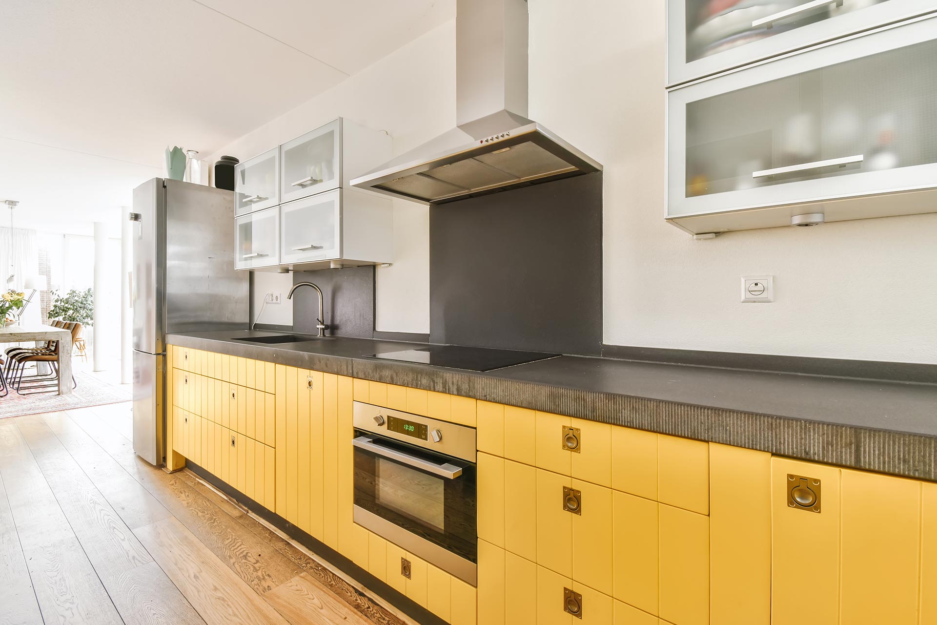 A kitchen featuring bright yellow cabinets paired with a sleek black countertop.