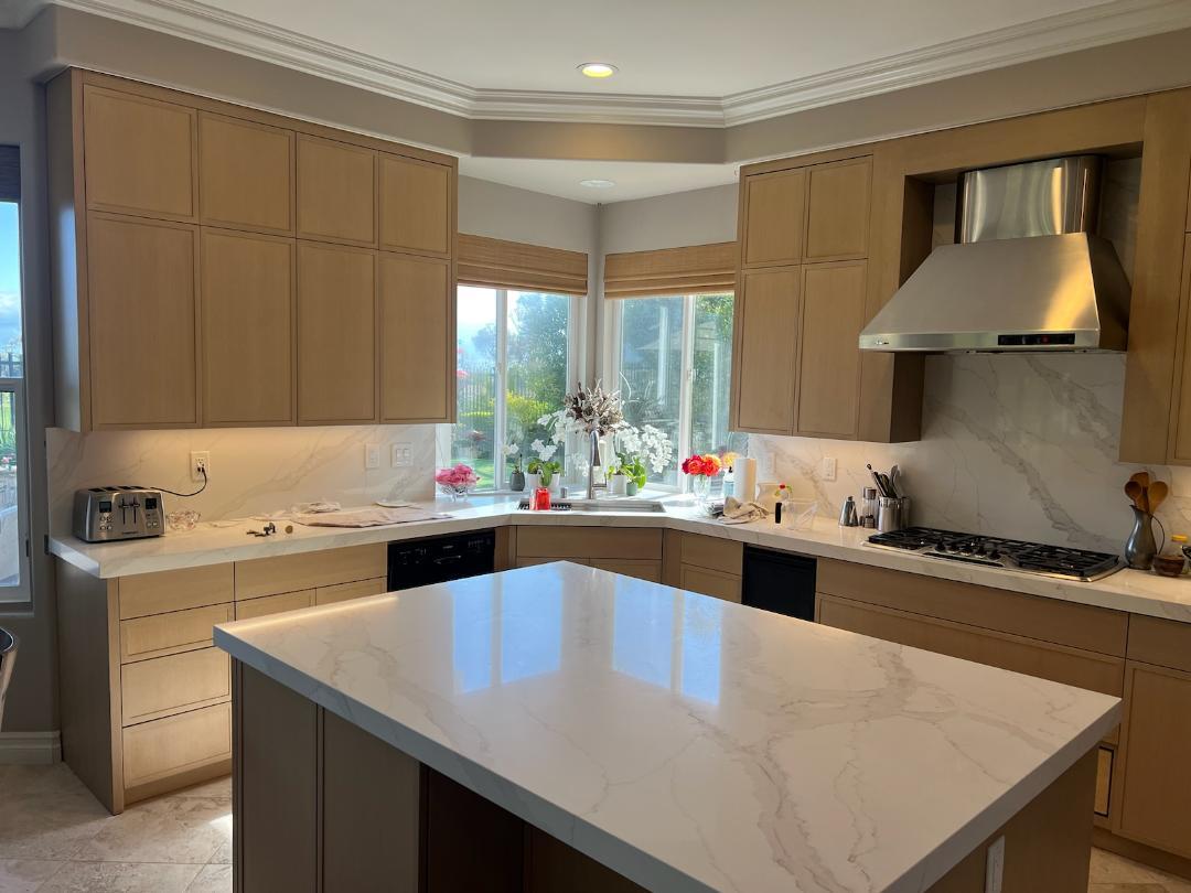 A modern kitchen featuring a large island with a sleek white marble countertop.