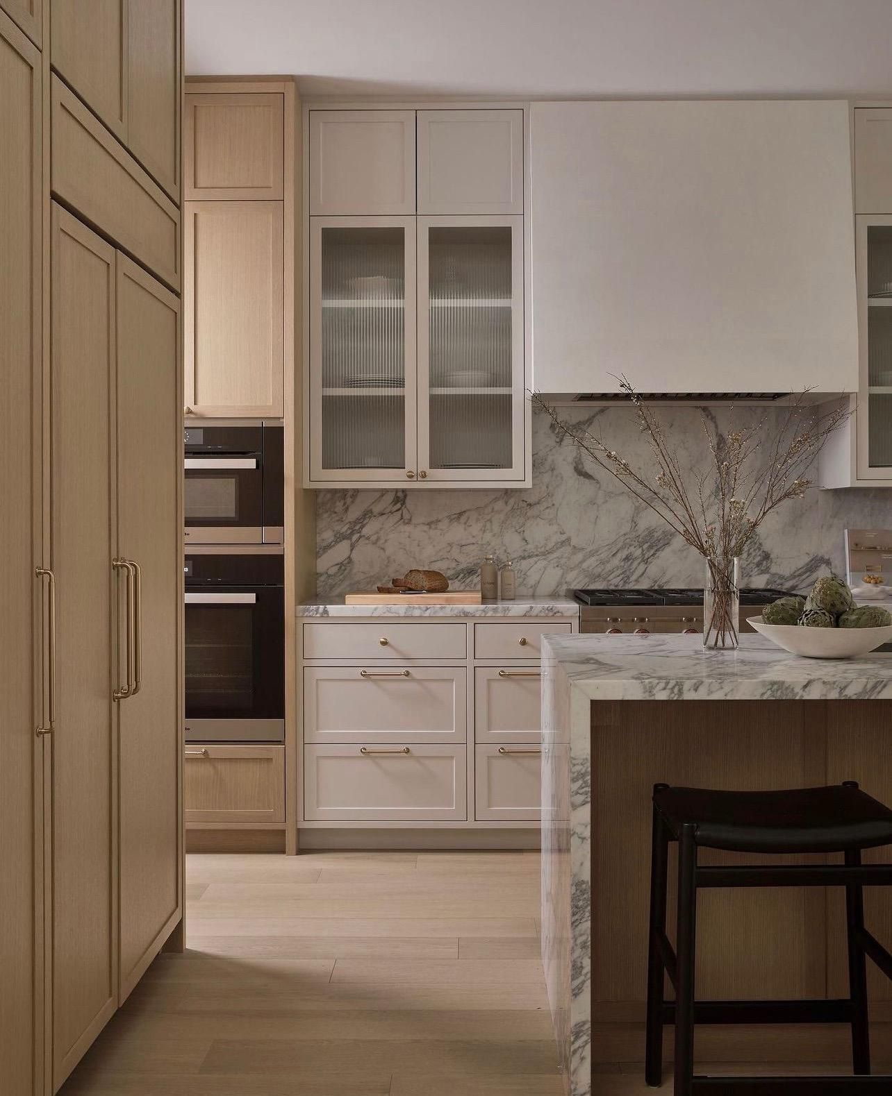 A modern kitchen featuring a marble island and elegant wooden cabinets.