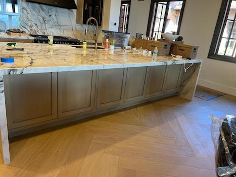 A modern kitchen featuring elegant marble countertops and warm wood floors.