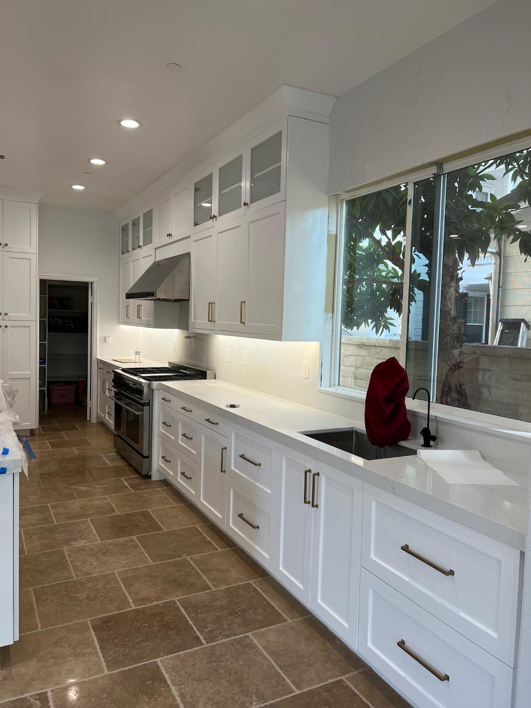 A modern kitchen featuring white cabinets and elegant tile flooring.